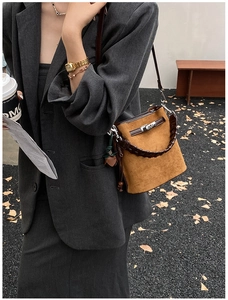 Detail of vintage brown suede bucket bag with silver twist lock and woven handle strap
