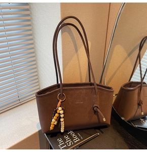 Detail of dark brown leather tote bag with braided bead pendant and knot detail