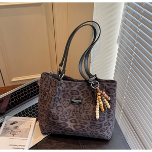 Close-up of leopard print tote bag with black handles and colorful beaded charm