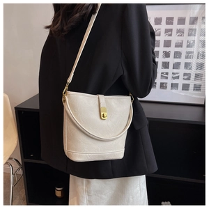 Detail view of a white bucket bag with gold lock buckle on a black blazer outfit