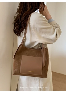 Close-up of a large suede hobo bag with contrast leather pocket shown on model