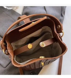 Detail view of woven brown bucket bag showing canvas lining and gold metal hardware