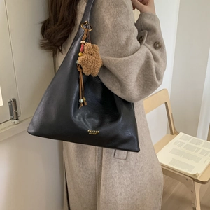 Close-up of black leather shoulder bag with gold logo and plush star charm accessory