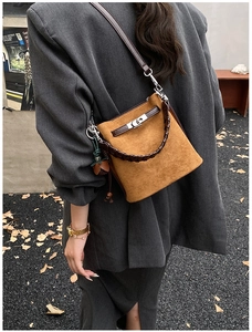 Detail of a brown suede bucket bag with metal twist lock and elegant fringe pendant