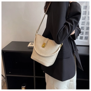 Detail view of cream leather bucket bag with gold twist lock and adjustable shoulder strap