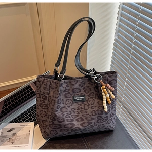 Close-up of leopard print tote bag with leather logo patch and wood bead tassel