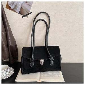 Detail of a vintage black suede underarm bag featuring a silver metal buckle closure