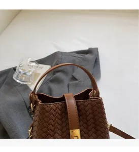 Close-up of brown woven bucket bag with smooth handle and elegant golden lock detail