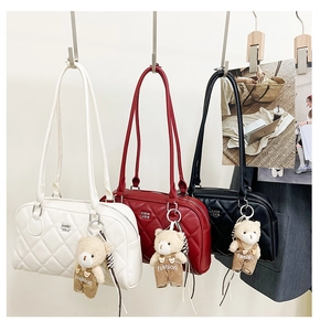 Close-up of quilted crossbody bags in white, red and black with plush bear charms