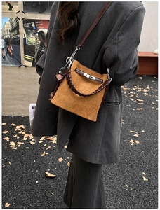 Detail of caramel suede bucket bag with leather braided handle and metal twist lock