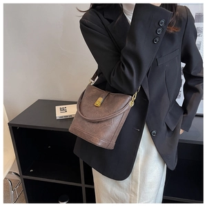 Close-up of deep brown lychee grain leather bucket bag with metal buckle and strap