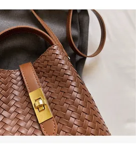 Detail shot of brown woven leather handbag with metallic gold twist lock and fine strap
