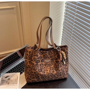 Detailed view of the leopard print tote bag with leather straps and decorative bead charm