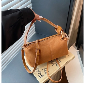 Detail of caramel suede cylinder bag featuring gold ring hardware and textured finish