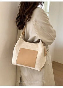 Detail view of retro suede tote bag with contrast pocket on a model in minimalist setting