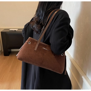 Detailed view of the dark brown suede tote bag featuring fine stitching and metal logo