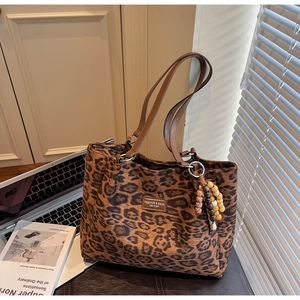 Detail of leopard print tote bag with metal nameplate and brown leather shoulder strap