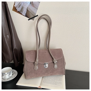 Detail of vintage suede shoulder bag with silver metal turn-lock on a retro book
