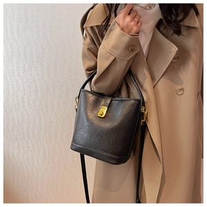 Detail of a vintage black leather bucket bag with gold twist lock and crossbody strap