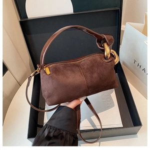 Detail of luxury brown suede handbag with large gold metal rings and smooth top zipper