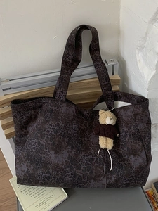 Large leopard print tote bag with a cute bear charm in a stylish indoor lifestyle setting