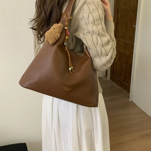 Brown leather tote with contrast stitching, logo detail and decorative charms