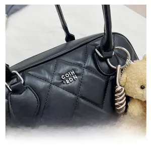 Detail of black quilted leather handbag featuring silver hardware and a cute bear charm
