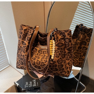 Detail of leopard print tote bag featuring brown leather handles and beaded charm