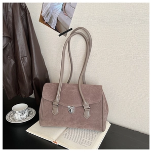 Close-up of retro mocha suede shoulder bag with metallic swivel clasp on books