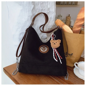 Gros plan du sac cabas noir givré avec logo M et un joli pendentif d'ours en peluche