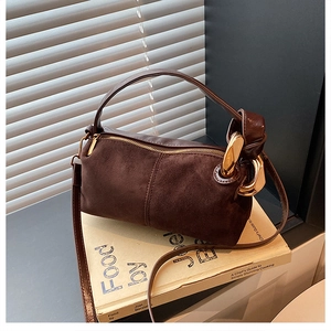 Detail of vintage brown suede leather handbag with gold metal ring and handle knot