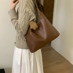 Brown leather hobo shoulder bag with plush bear charm and gold logo detail on large tote