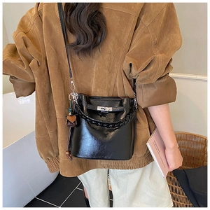 Detail of a black leather bucket bag with woven handle and metallic lock in chic home setting
