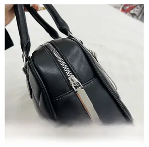 Detail of a smooth silver metal zipper on a black quilted leather handbag for women