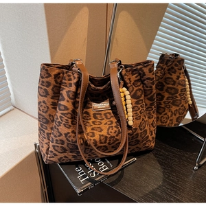 Close-up of leopard print tote bag with brown leather straps and beaded charm detail