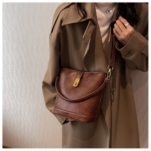 Detail of vintage brown leather bucket bag featuring a gold twist lock and crossbody strap