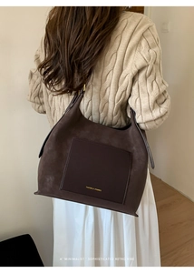 Close-up of deep brown suede tote bag with contrast leather pocket and gold brand logo