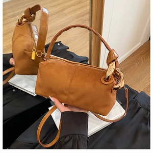 Detail of tan suede handbag with gold circular metal handle and knotted strap design