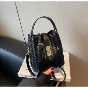 Detail of woven black bucket bag featuring golden hardware and leather texture