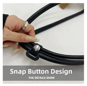 Detailed view of the silver metal snap button and stitching on a black leather handbag
