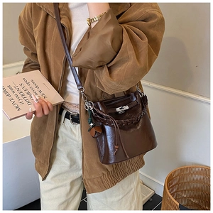 Detailed shot of dark brown bucket bag featuring woven handle and silver twist lock closure
