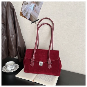 Detail showing deep red matte suede shoulder bag with a silver metallic twist lock