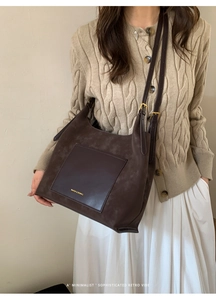 Close-up of retro suede tote bag with leather pocket and adjustable gold hardware