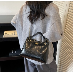 Details der schwarzen gesteppten Ledertasche mit goldenem Drehverschluss und Kettenriemen