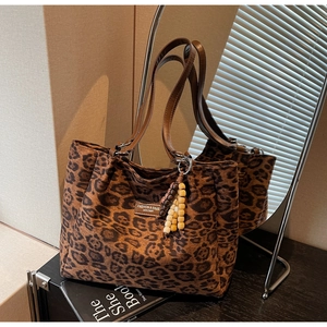 Detail of leopard print tote bag with brown leather handles and wooden bead tassel decoration