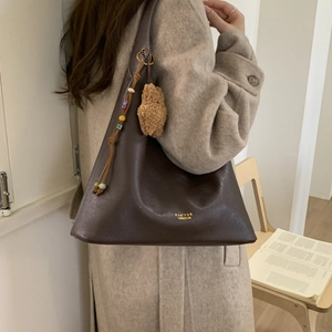 Detail of dark brown leather hobo bag with ethnic beads and plush bear charm