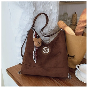 Gros plan d'un cabas vintage en daim marron avec pendentif ours et logo M