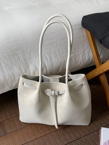 Minimalist beige large capacity tote bag with buckle detail on a domestic interior background