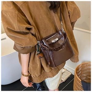Detailed view of deep brown patent leather bucket bag with silver twist-lock and charm