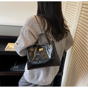 Detailansicht der schwarzen gesteppten Ledertasche mit goldener Kette am Modell